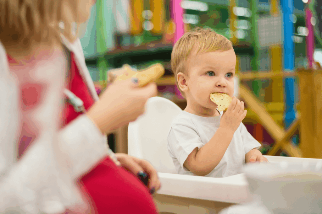 Children sitting at a nursery table eating lunch together.
