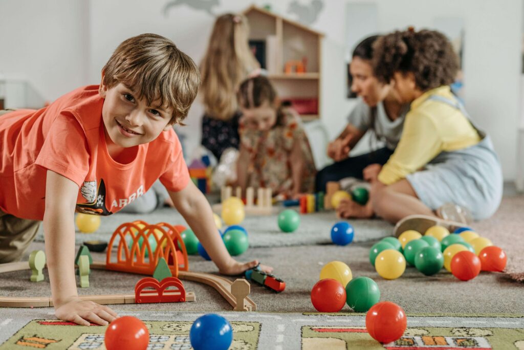 Clean, colourful playroom with children on the floor playing.