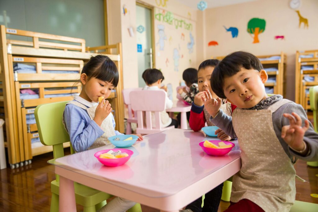 Children sharing a healthy meal at a nursery table.