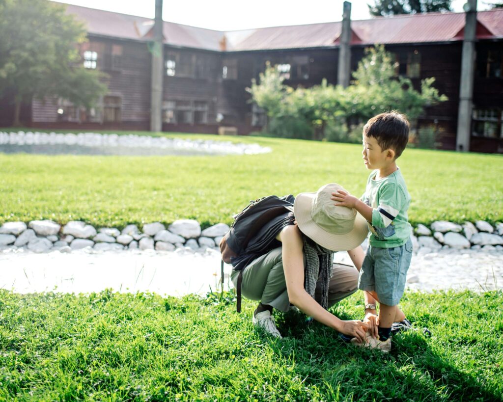 Child putting on shoes or coat with parent’s help.